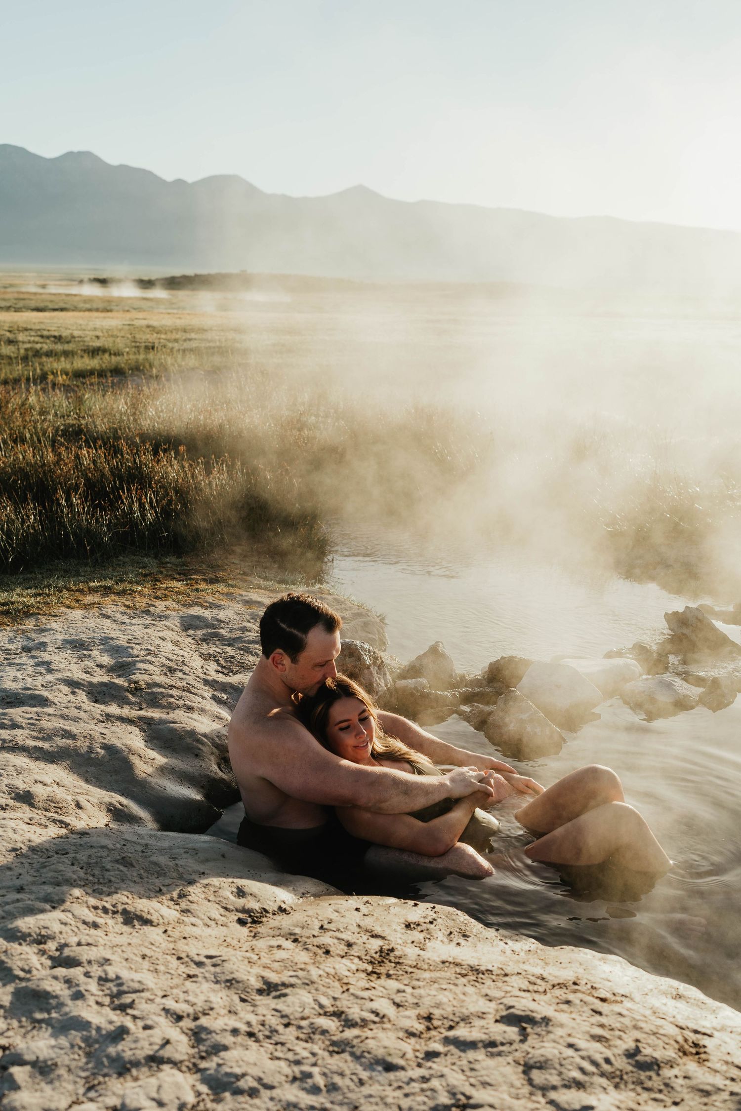 A couple shares an intimate moment dancing together on a wooden deck at dusk surrounded by moody forest scenery.