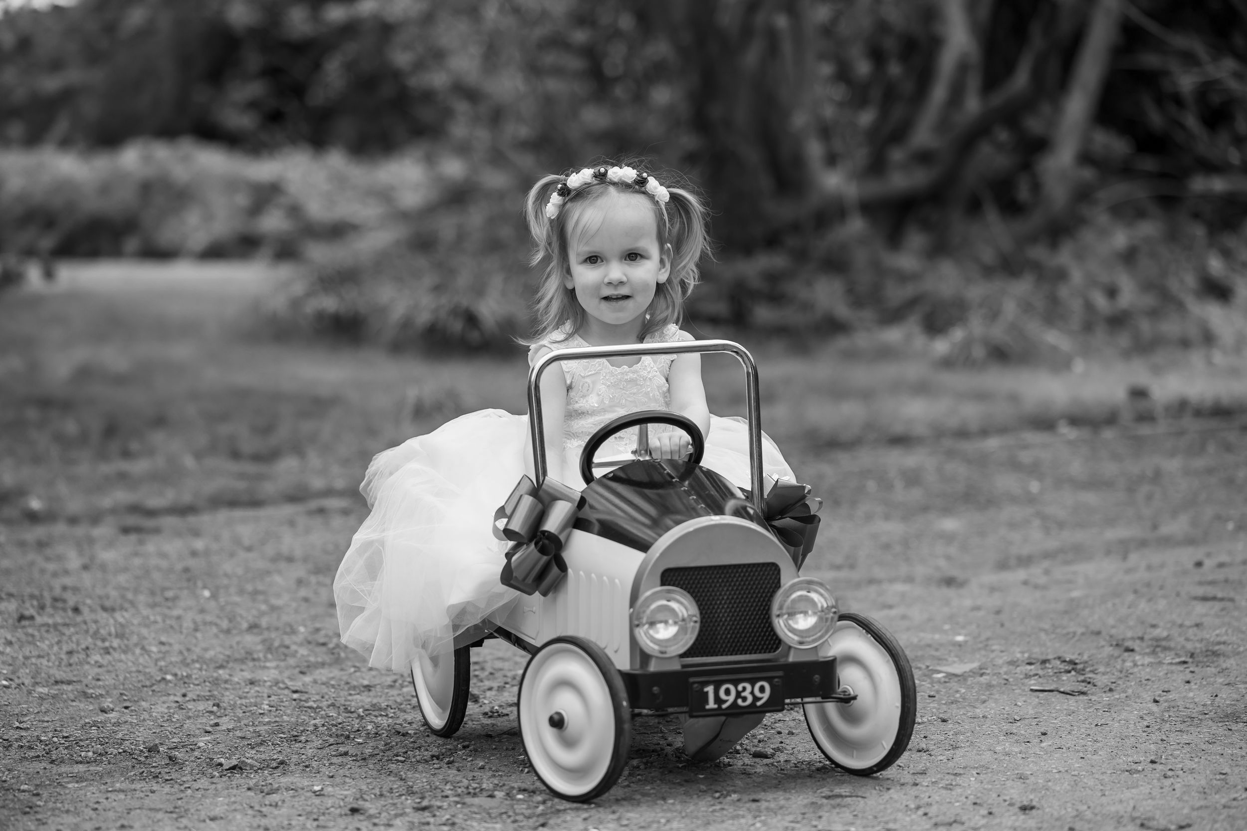 Vintage pedal cars lined up in black and white showing progression in model design through the years.