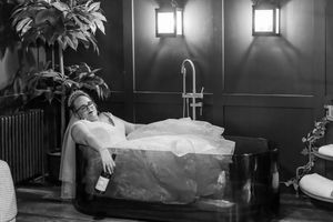 Woman lies gracefully in a bath in an art deco style black and white photograph.