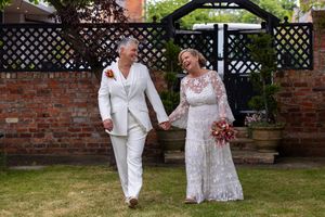 A couple in white and floral attire share a joyful dance moment together in a garden setting. Casual Captures Wedding Photography