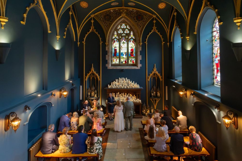 Elegant wedding ceremony in a stunning blue Gothic chapel with stained glass windows and candlelit altar.