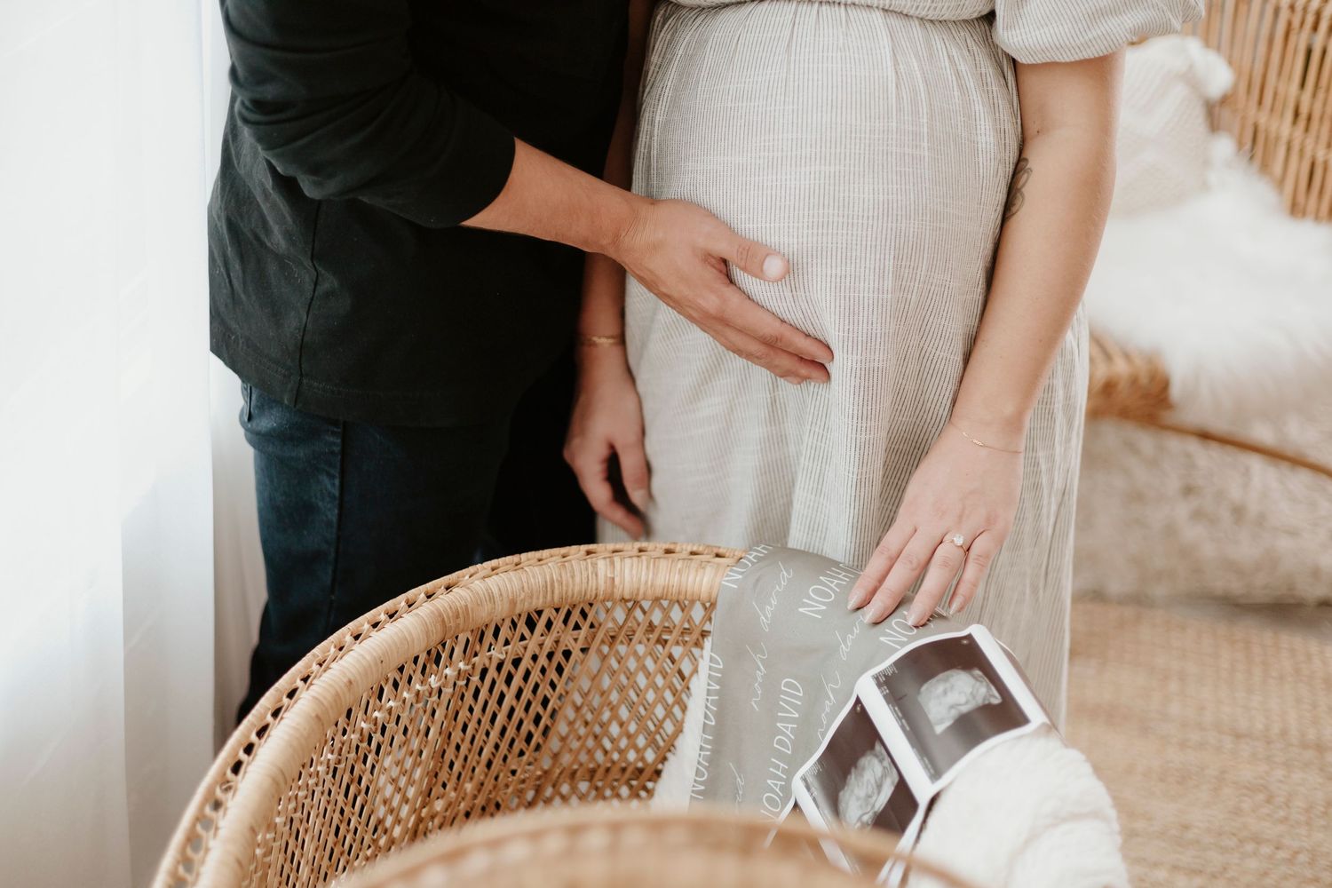 A close-up of hands near a wicker chair with ultrasound photos visible.