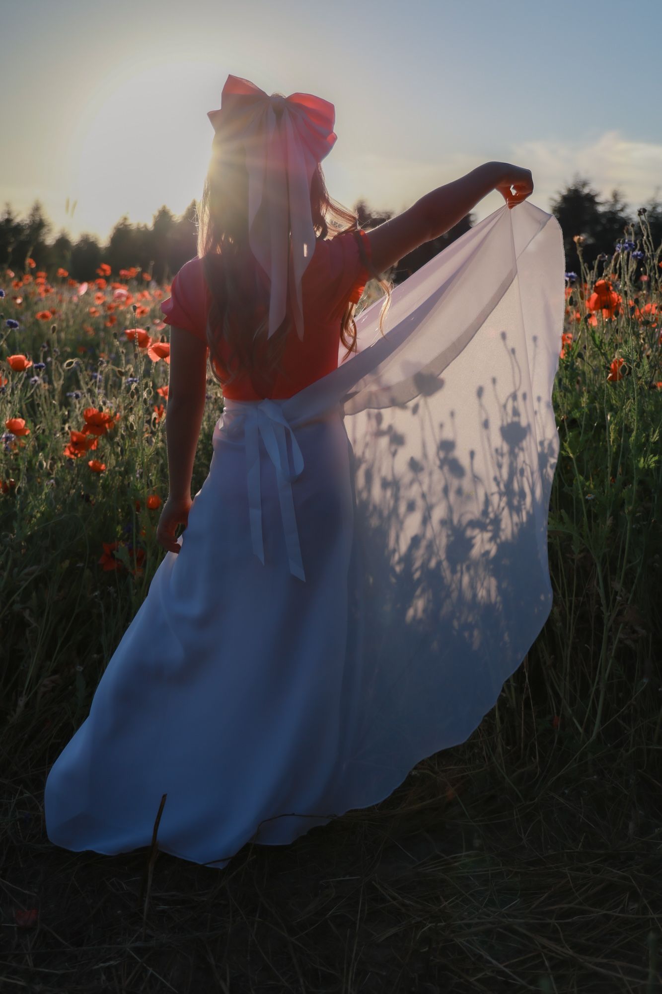 Woman in cowboy hat and denim jacket stands in autumn field wearing western attire.