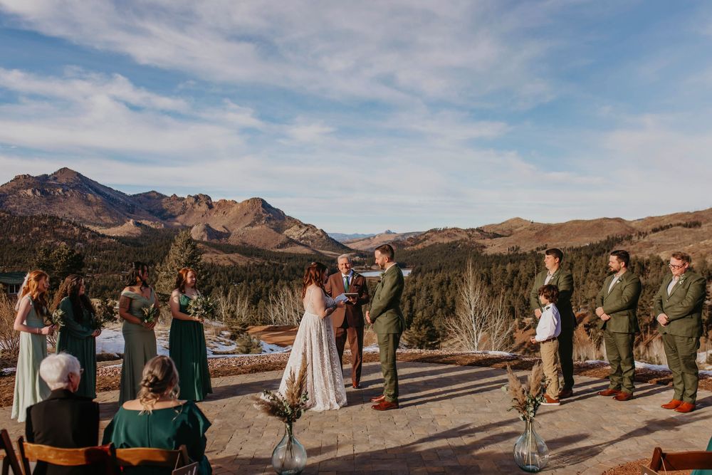 Outdoor desert wedding ceremony with mountains and blue sky in the background.