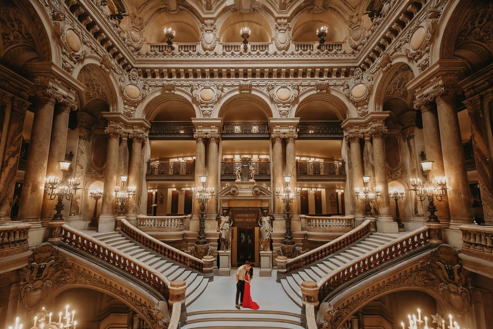 Ornate grand staircase and baroque architecture inside a historic opera house with gilded details and crystal chandeliers.