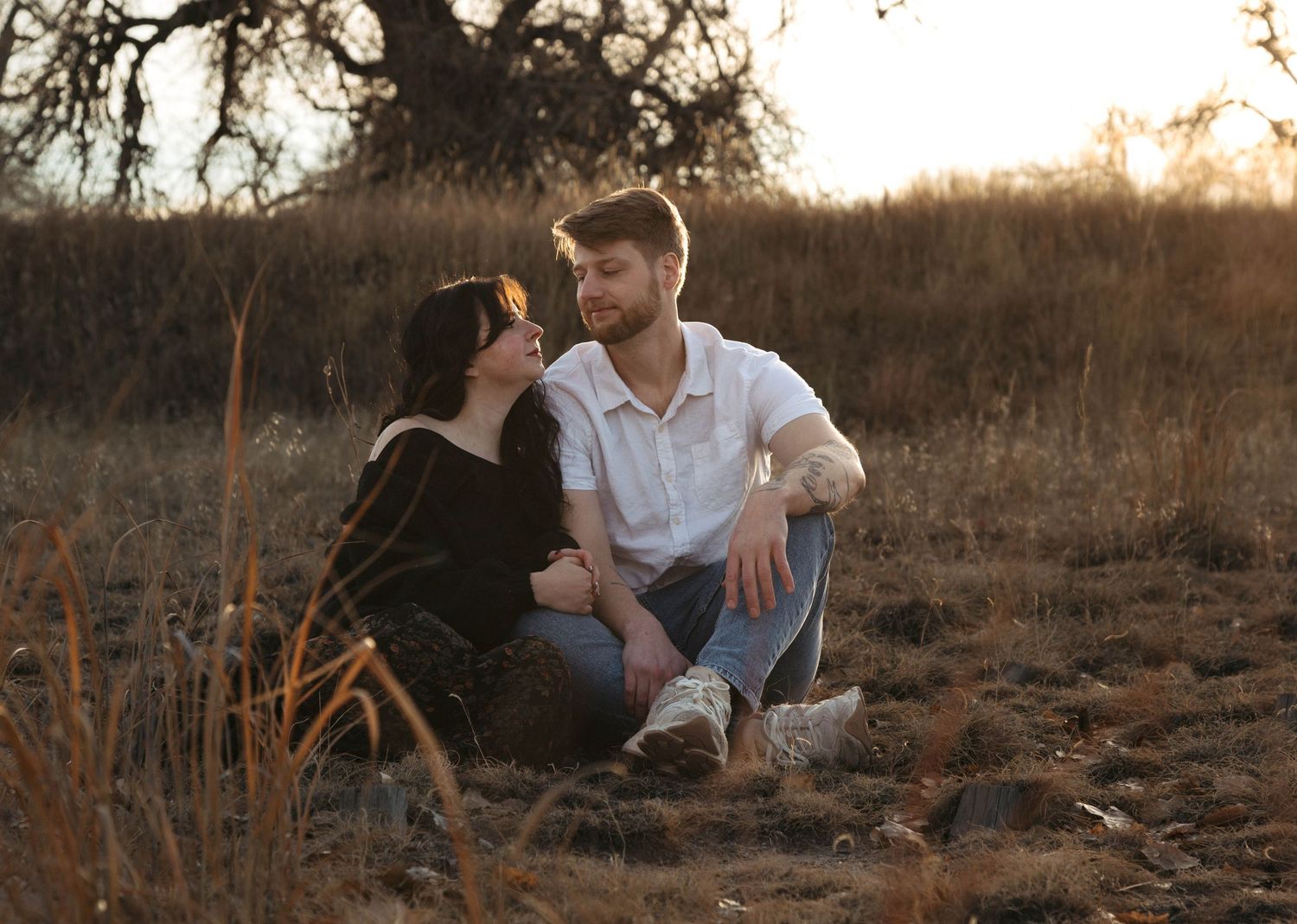 Two people sitting together on grass having an intimate conversation in a park setting.