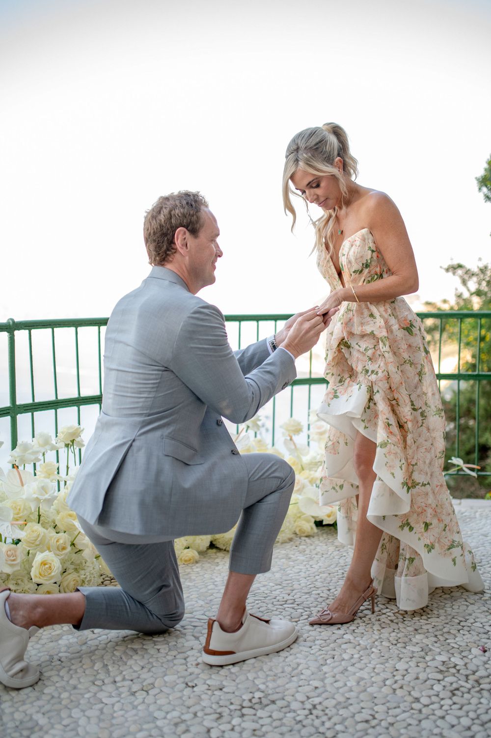 Marriage proposal sequence showing couple on stone terrace with white flowers.