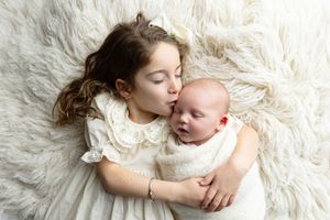 A tender moment captured on soft white fur with a gentle embrace between two people.