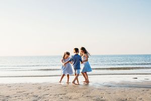 Group of people walking together on sandy beach at sunset along the ocean shore.