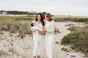 Two people in white outfits share an intimate moment while walking along a sandy beach path.