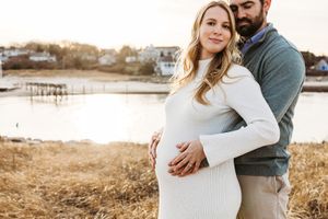 A couple embraces in a romantic outdoor photoshoot by a lake during golden hour.
