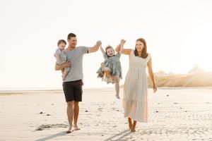 A family enjoying a carefree walk together along a sunlit beach at golden hour.