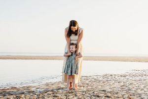A tender moment between parent and child playing together on a sandy beach at sunset.