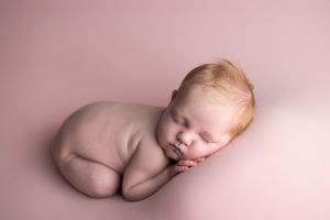 Artistic series of minimalist nude newborn photography poses against soft pink backgrounds.