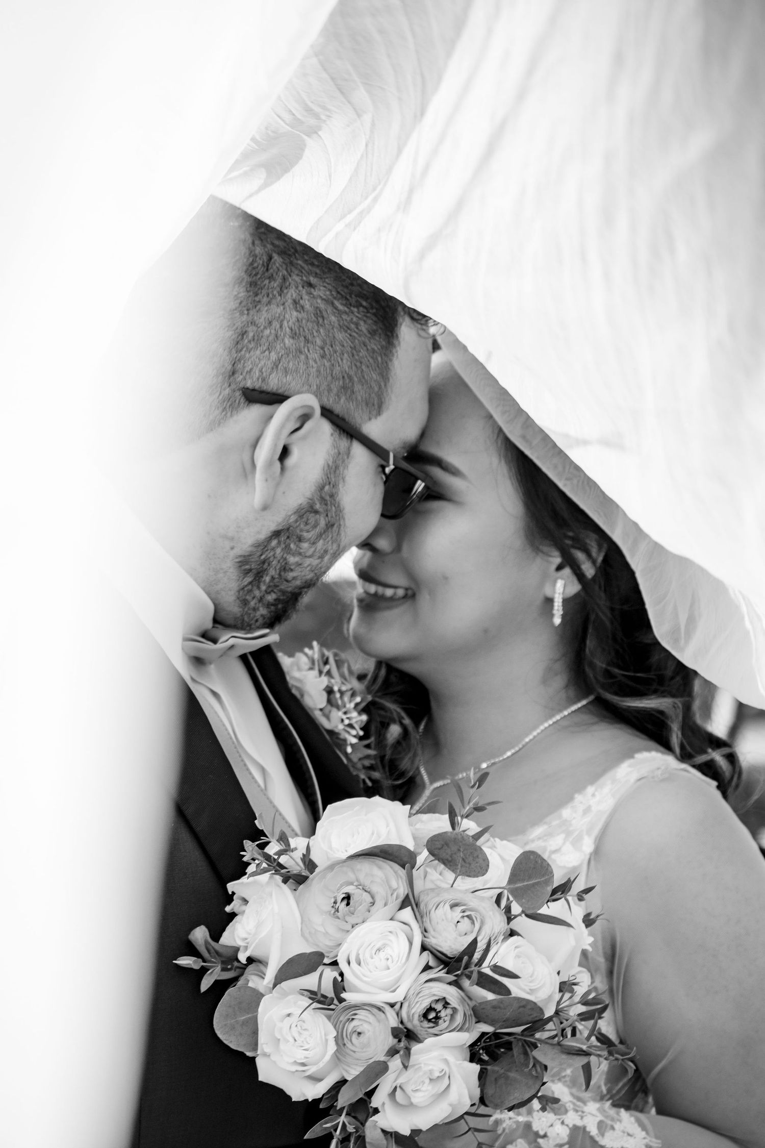 Intimate black and white wedding portrait with white roses and elegant attire.