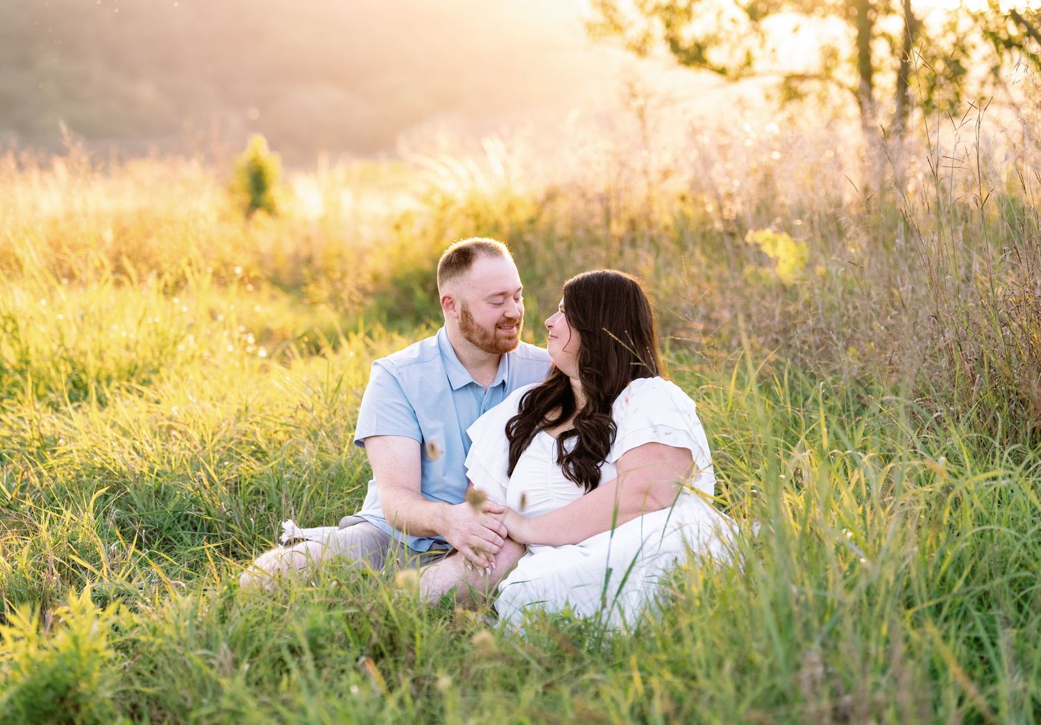 Couple shares intimate moments in a golden sunlit meadow during sunset.