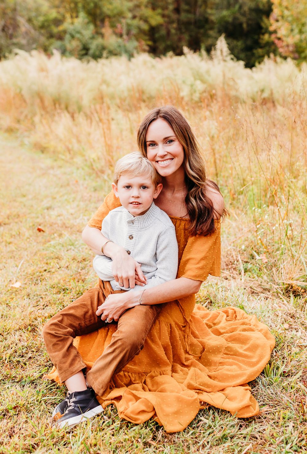 A heartwarming family photoshoot in a golden autumn field with warm orange tones and natural lighting.