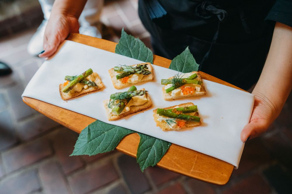 Appetizers being plated on white serving boards with fresh herbs and garnishes.