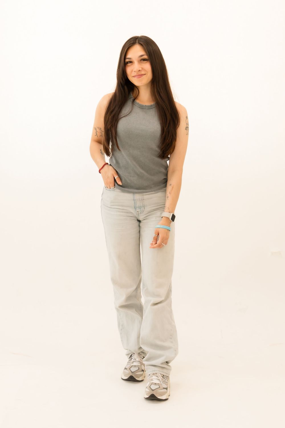 Girl with one hand in her pocket in a studio with a white background.