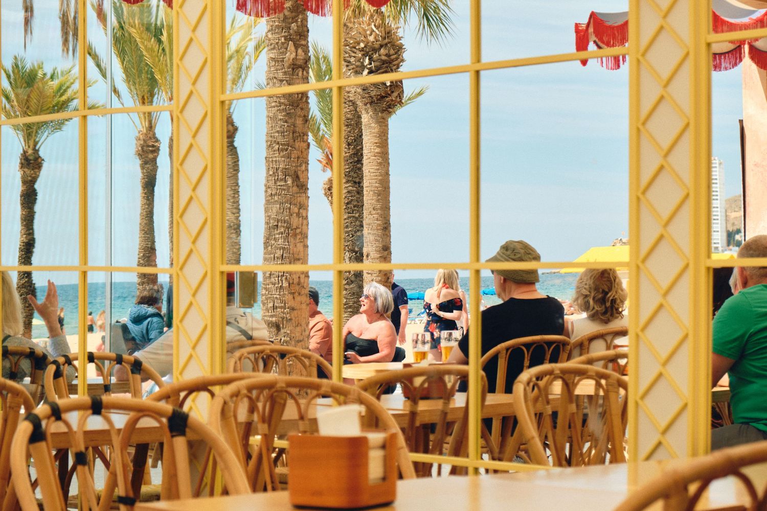 Outdoor beach restaurant with palm trees and wooden furniture offering seaside dining.