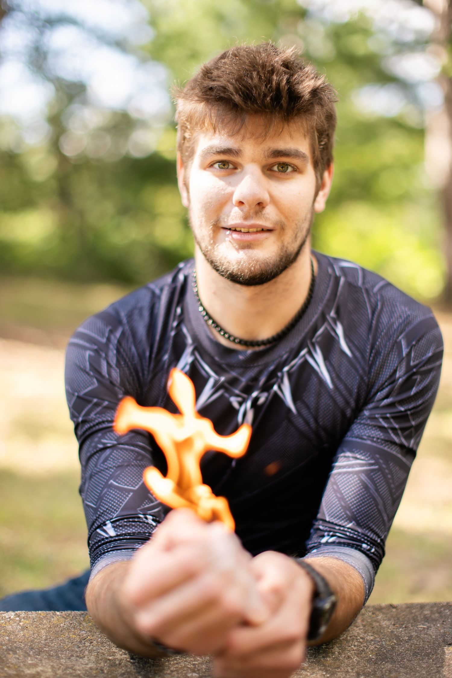 Person in black long sleeve shirt creates fire effect in outdoor portrait setting.
