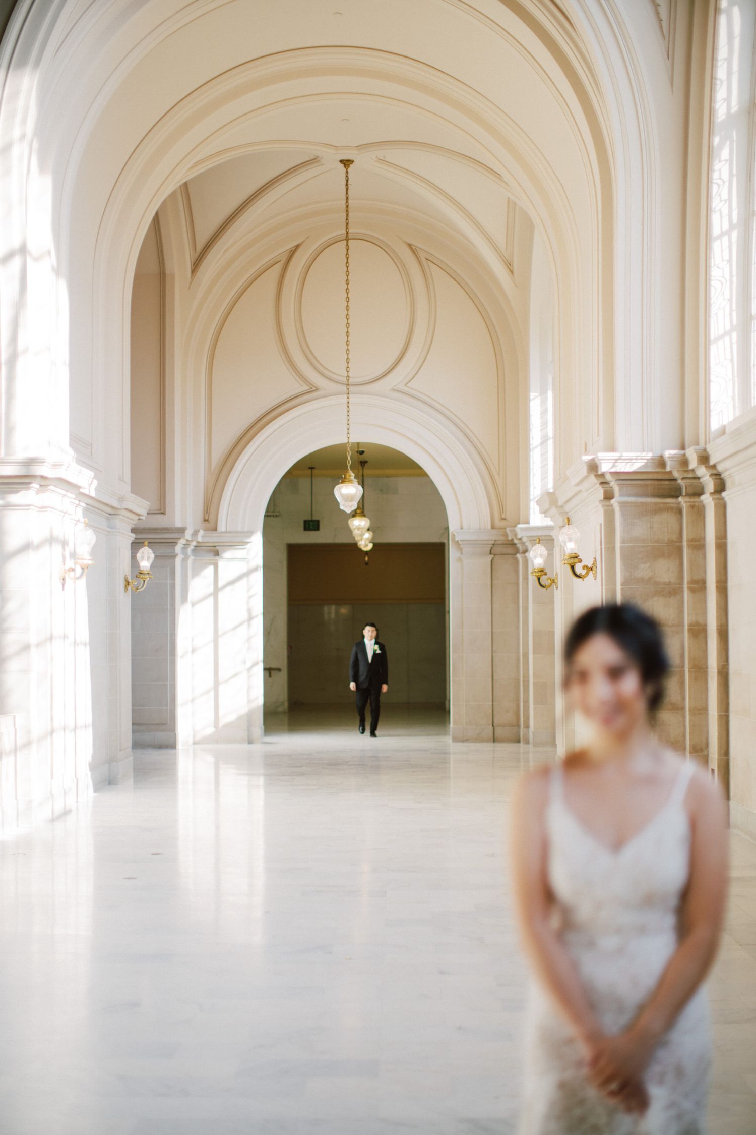 An elegant corridor with arched ceilings and natural light streaming through windows.