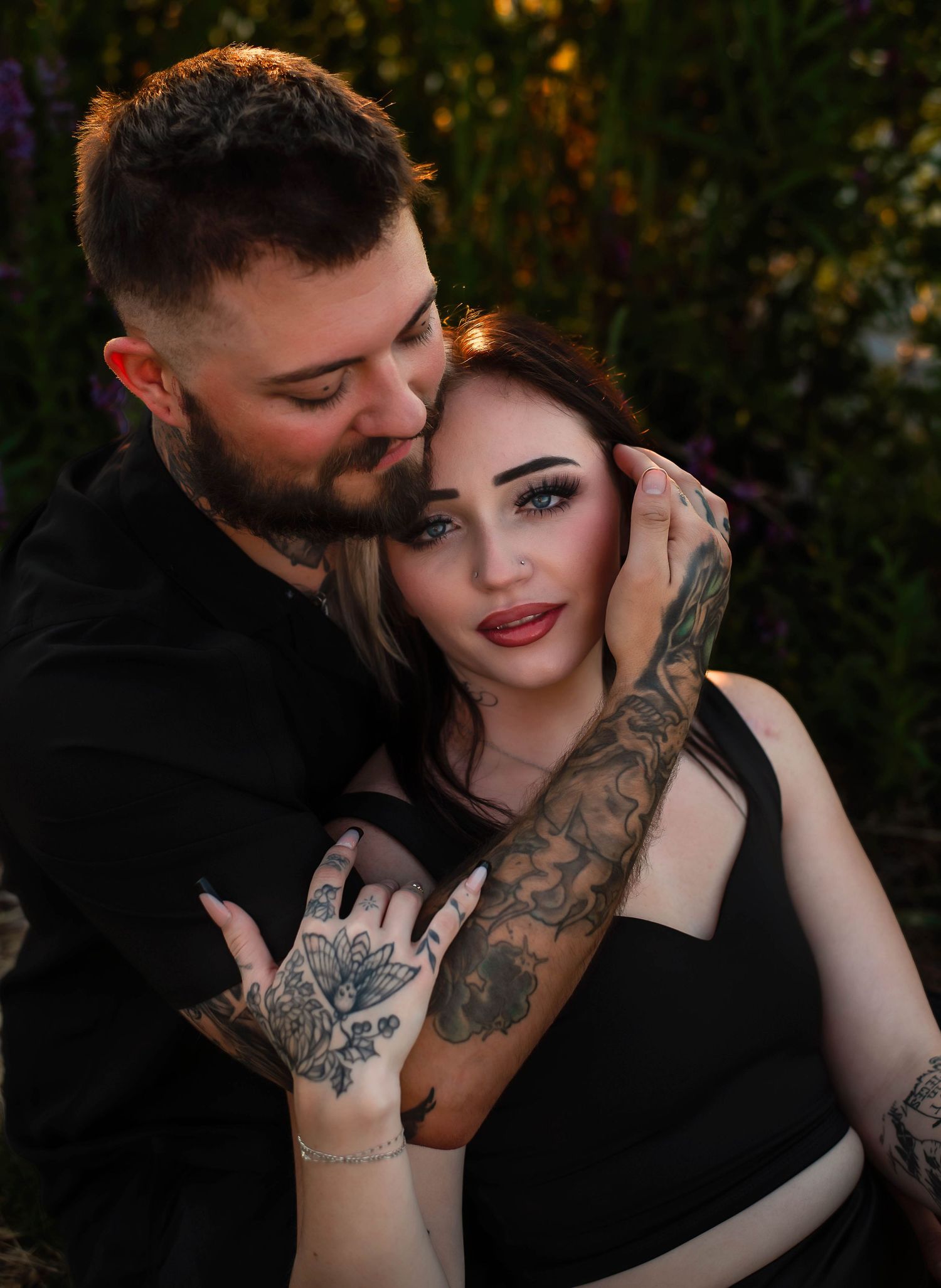 gorgeous couple in all black. woman is sitting against her future husband