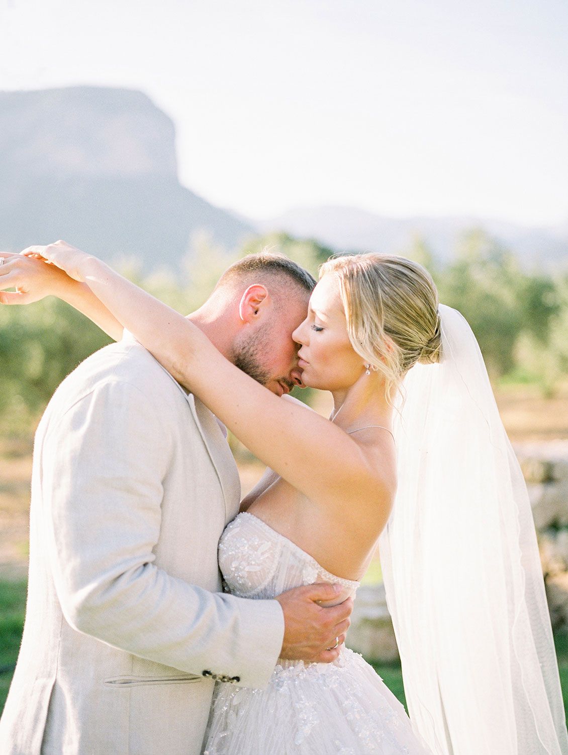 A romantic wedding couple shares an embrace in front of scenic mountain views on their special day.