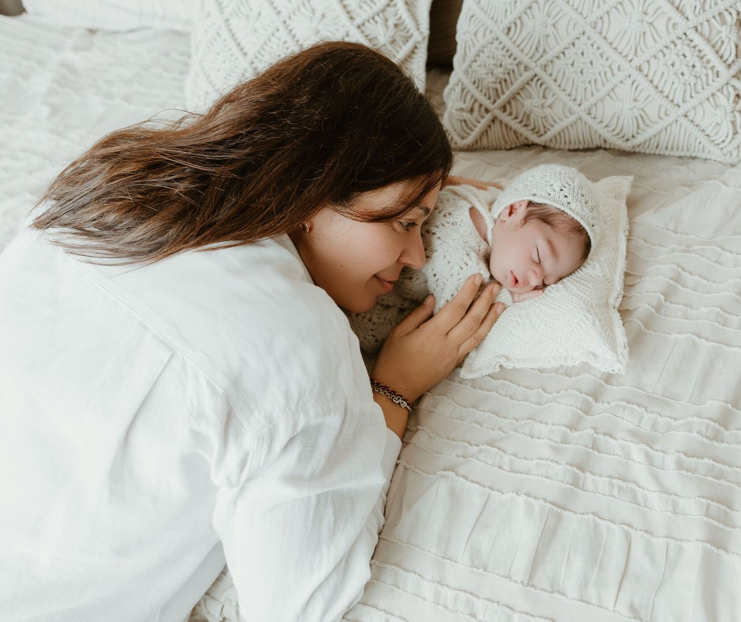 Sesión newborn en Valencia con un dulce retrato familiar en tonos neutros, sobre una pared tejida decorativa y rodeados de elementos natural