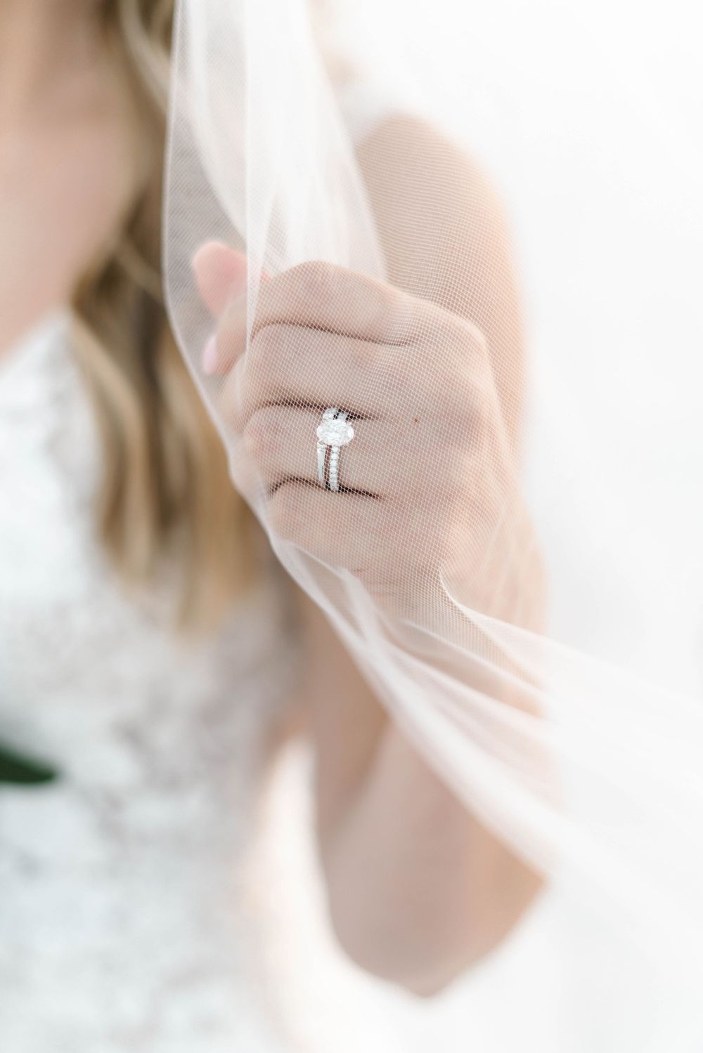 Close-up of diamond engagement ring through delicate wedding veil.