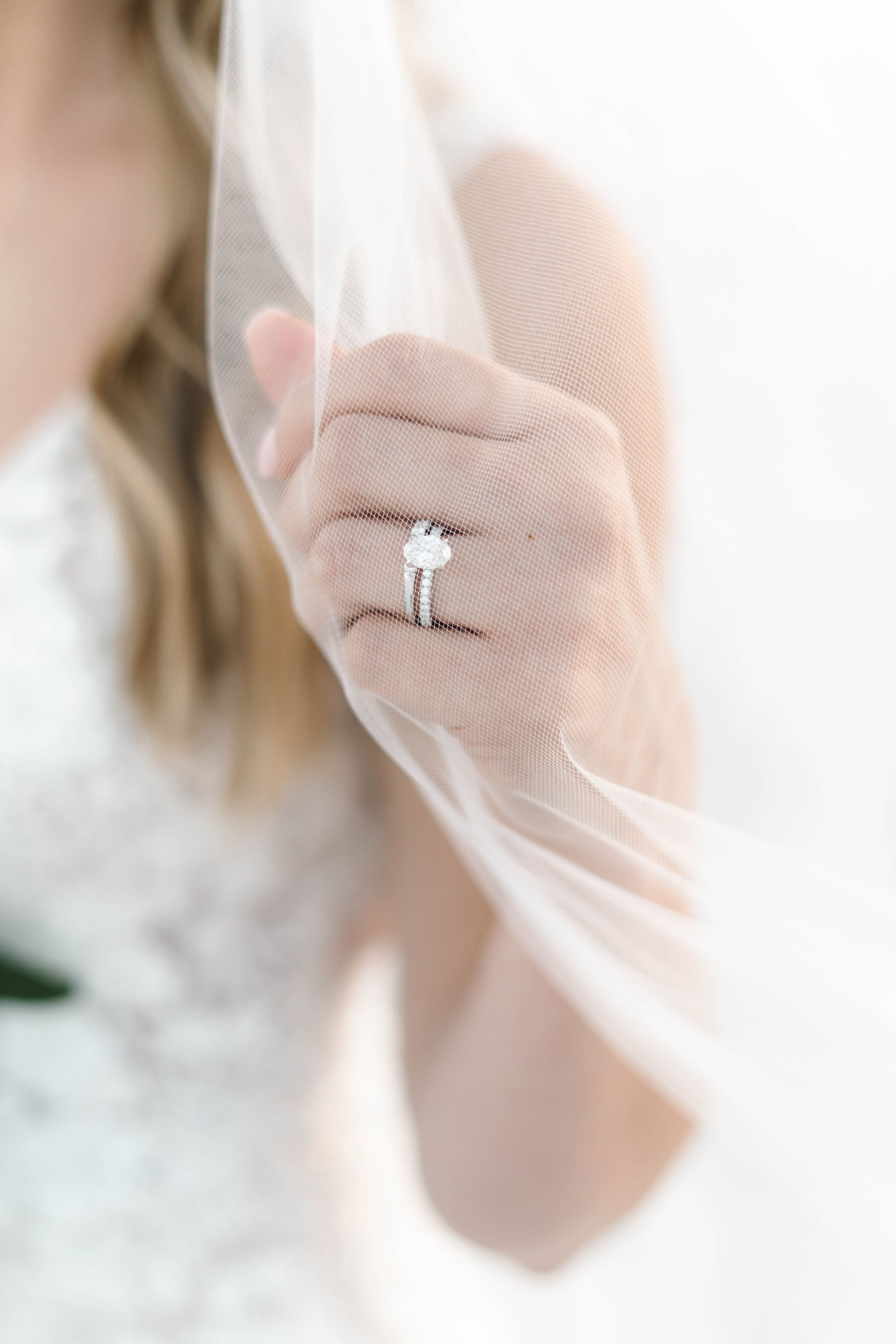 Close-up of diamond engagement ring through delicate wedding veil.