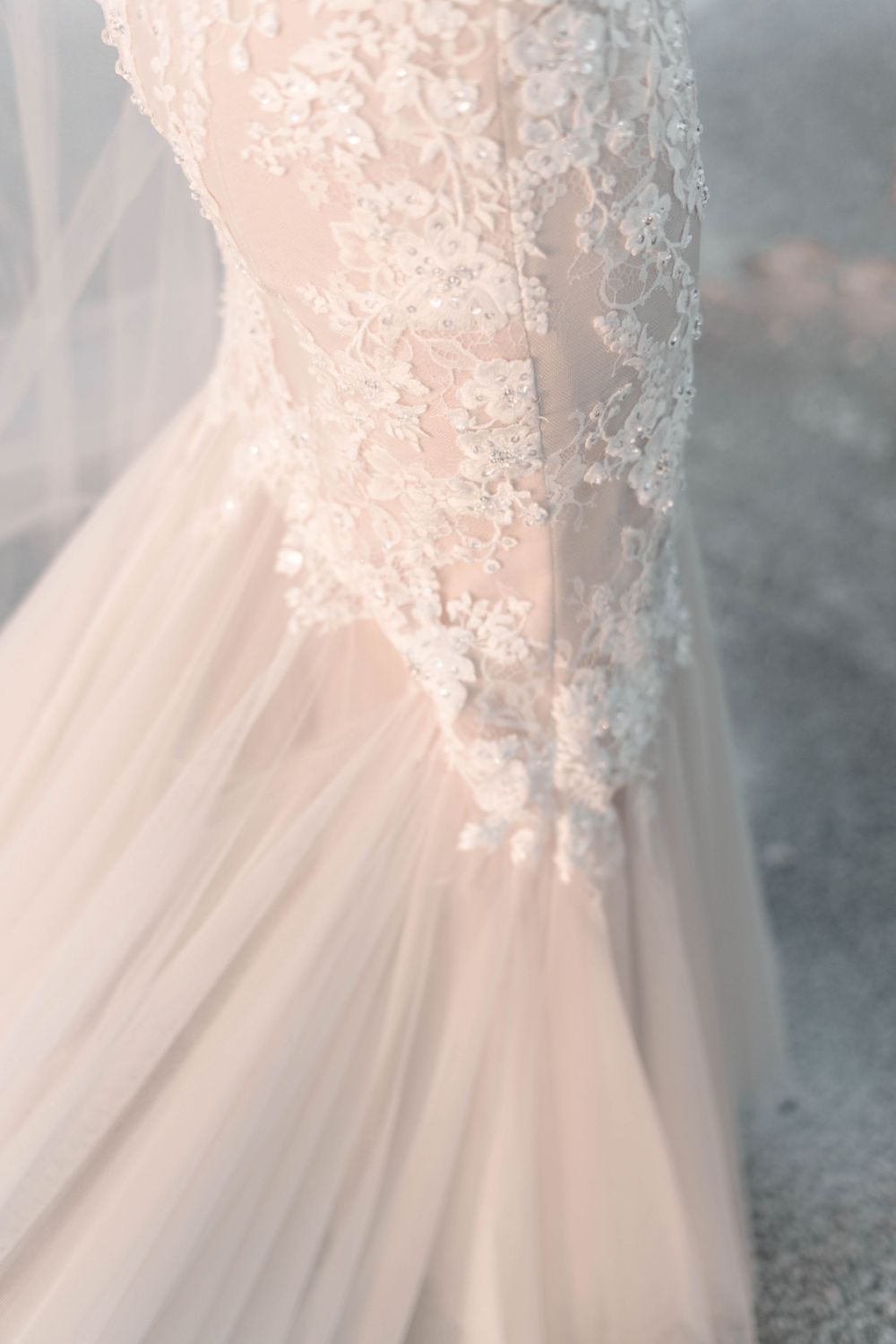Close-up detail of delicate lace and tulle on a blush wedding dress.