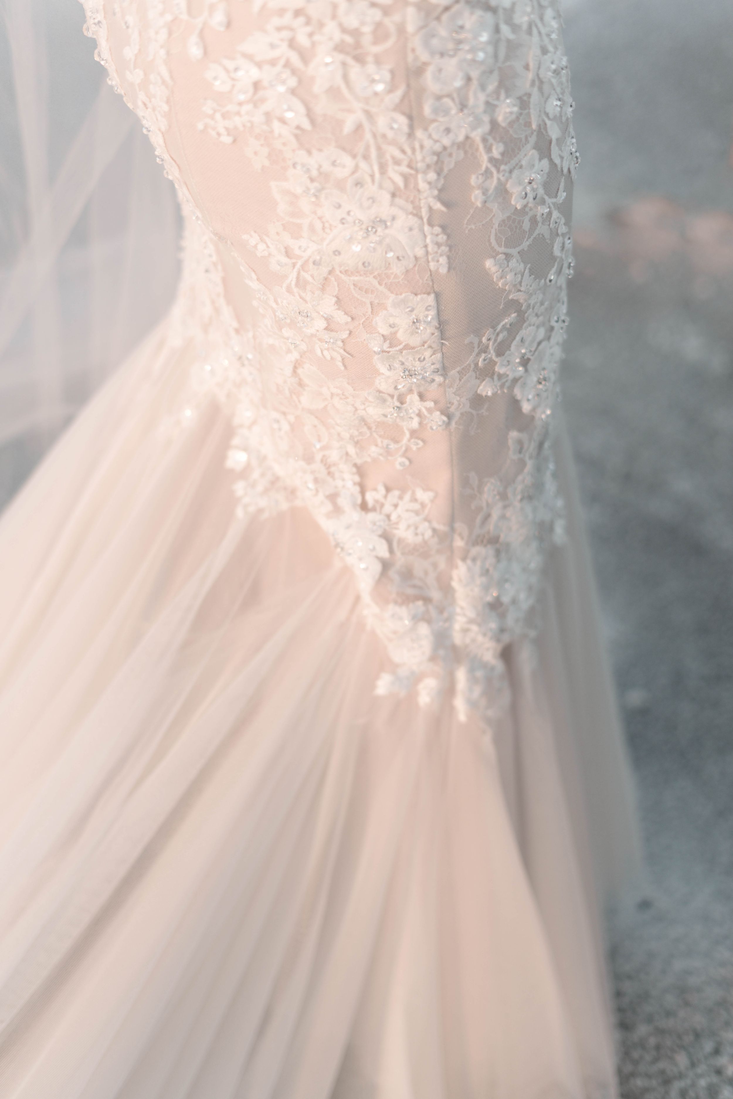 Close-up detail of delicate lace and tulle on a blush wedding dress.