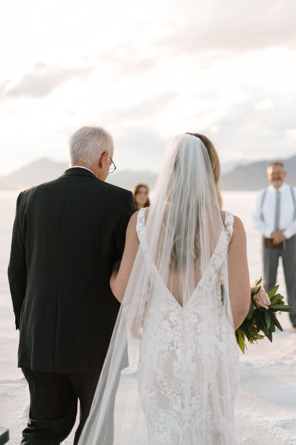 Wedding ceremony processional on white salt flats with mountains in background.