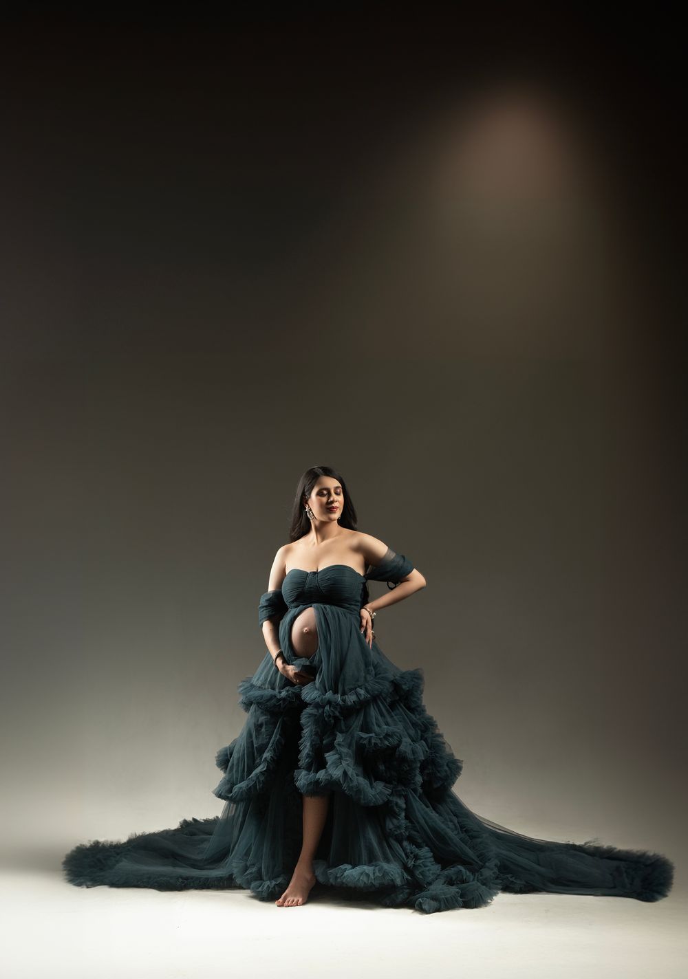 Dramatic black tulle gown with sweeping train photographed against dark background.