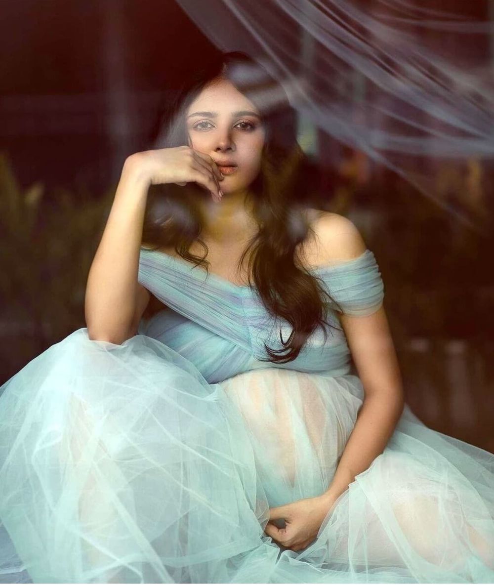 Dreamy portrait in soft light featuring a flowy light blue tulle gown against a dark background.
