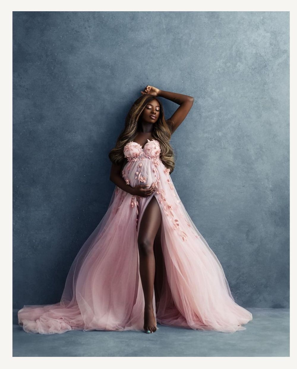 Stunning pink tulle maternity gown with high slit and sweetheart neckline against grey backdrop.
