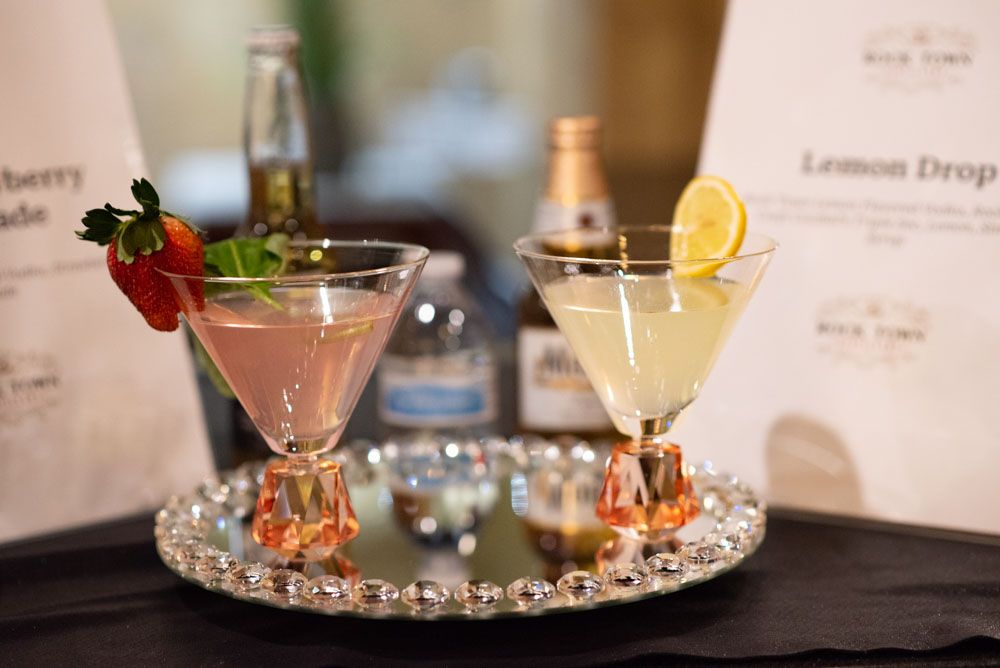 Artfully presented cocktails with citrus garnishes on an illuminated bar display.