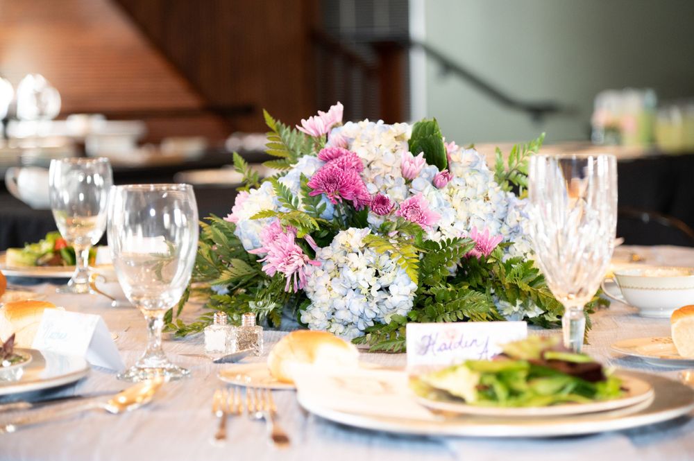 Elegant table settings with colorful floral centerpieces and wine glasses at a formal dining event.