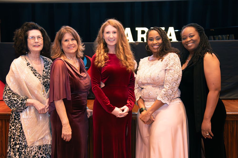 A group of people posing together at a formal event wearing elegant dresses.