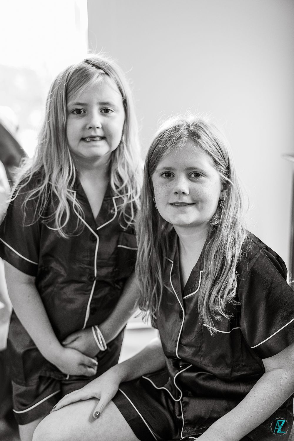 Two children wearing matching black satin pajamas with white piping.