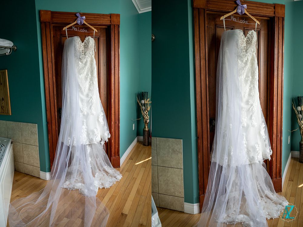 White wedding dress with lace details displayed against teal walls and wooden trim.