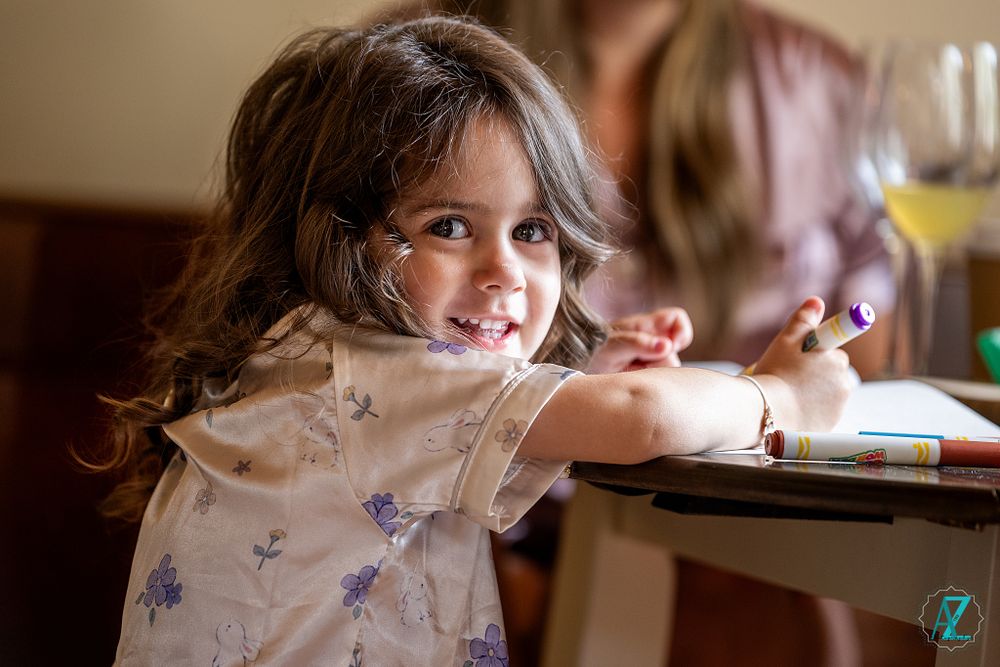 A young guest at a celebratory event sitting at a table.