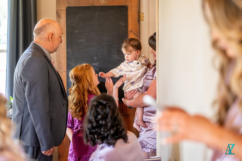 A small group gathers around a chalkboard during a wedding preparation moment.
