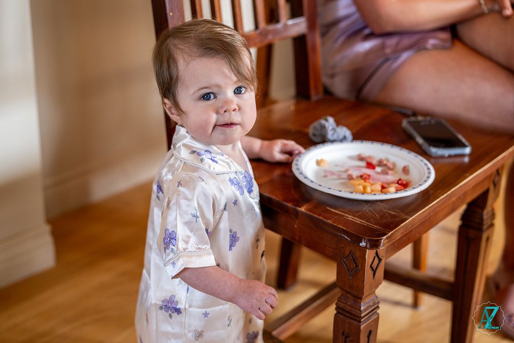 Young child in floral pajamas stands near a side table during wedding preparations.