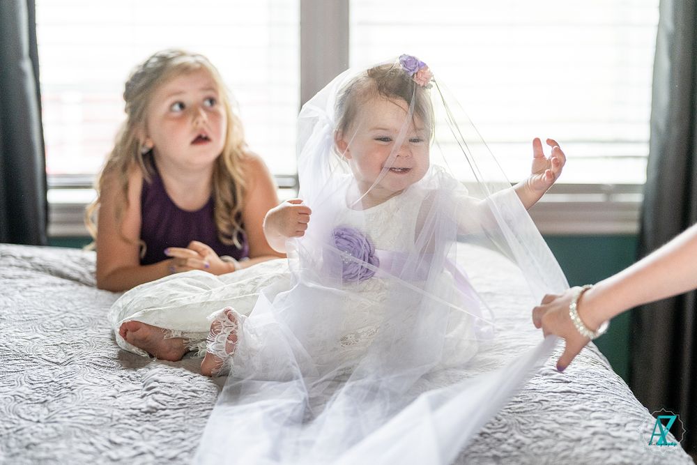 Playful moments captured on a bed with tulle and wedding preparations.