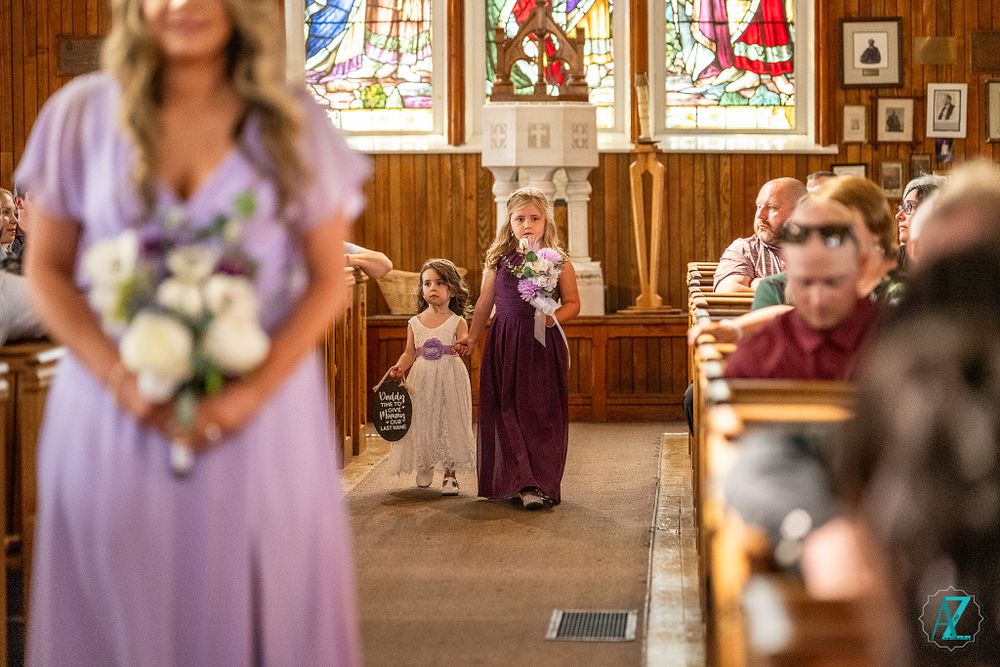 Church interior with stained glass windows and wedding attendants walking down aisle.