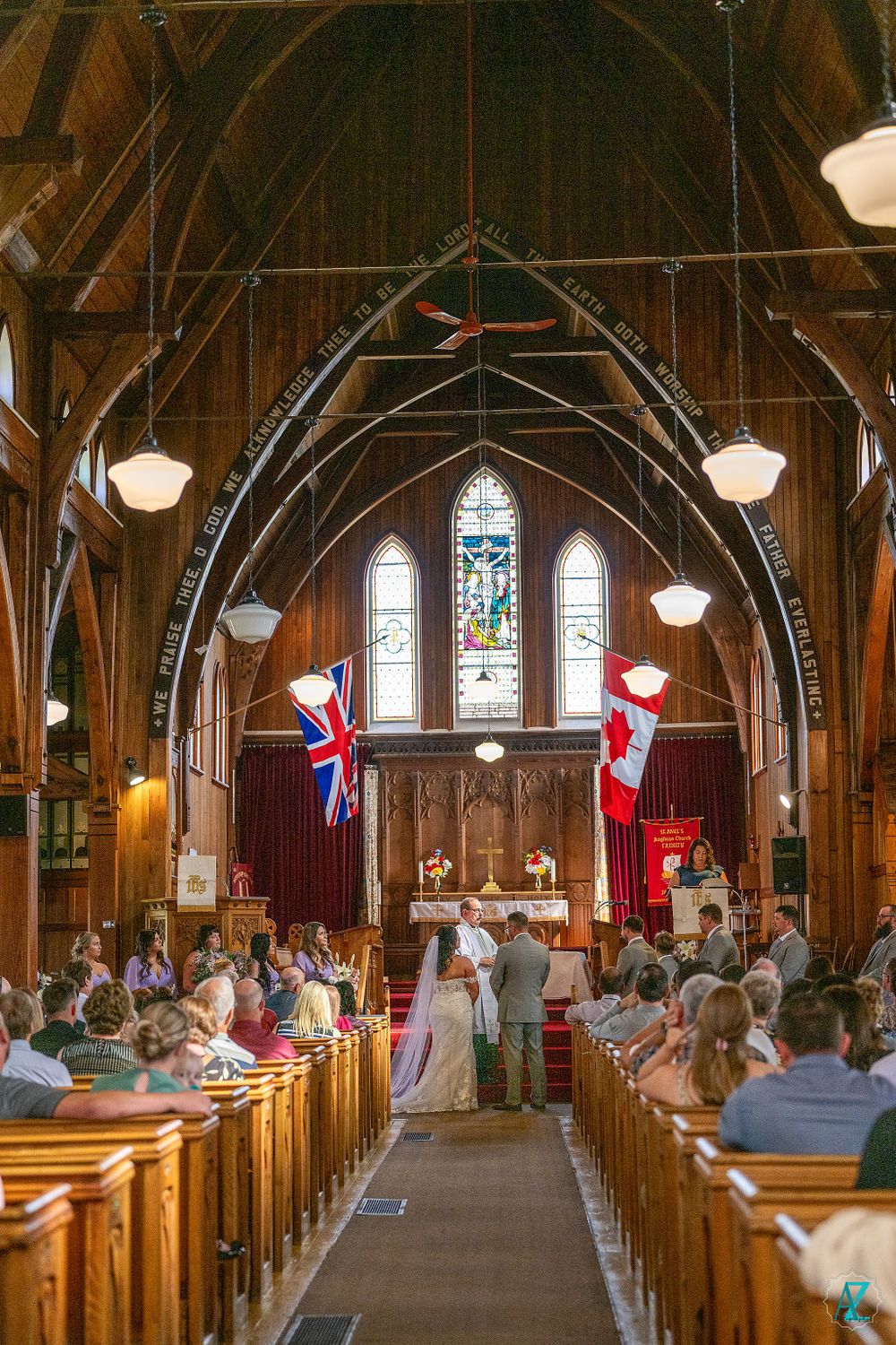 Sunlit church wedding ceremony with wooden architecture and national flags displayed.