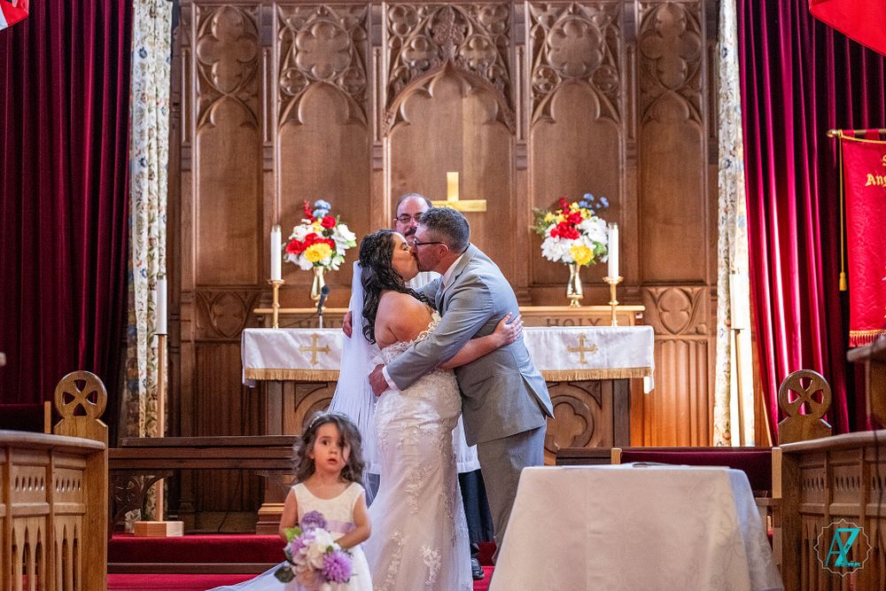 A couple shares their first kiss at the altar during their church wedding ceremony.