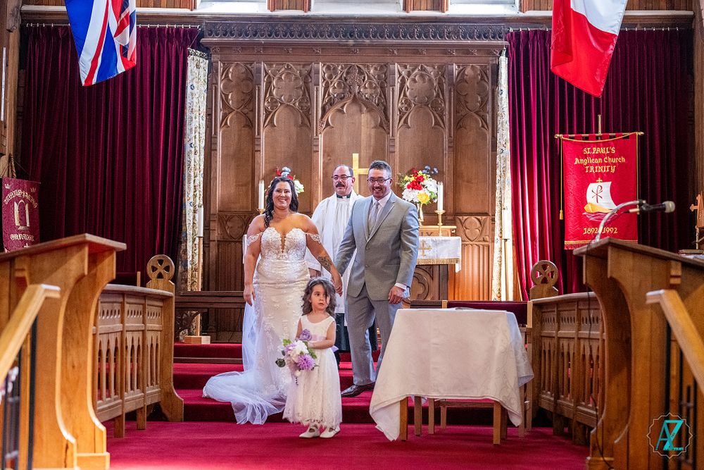 A celebratory moment captured at a church altar with flags and floral decorations.